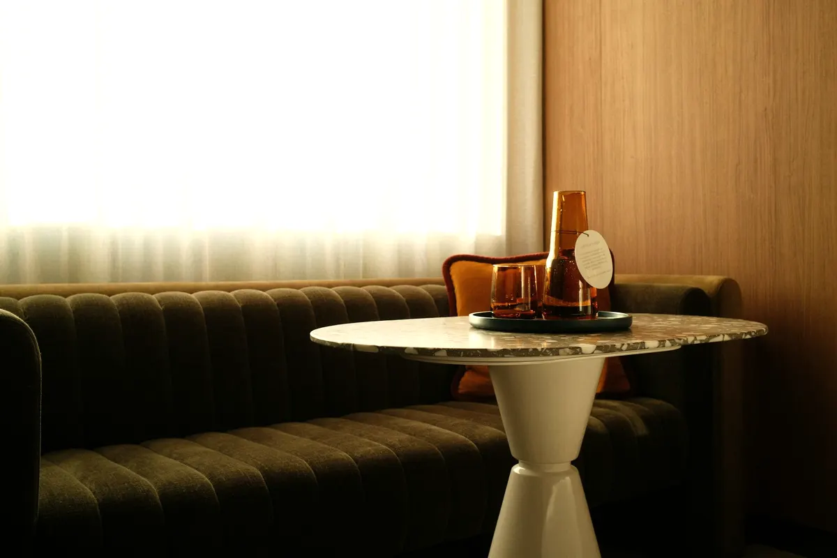Runder Marmortisch mit Karaffe und Gläsern vor dem Sofa
